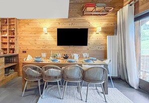 Ein Essbereich mit Holzwand, Flachbildfernseher und einem Büfett.