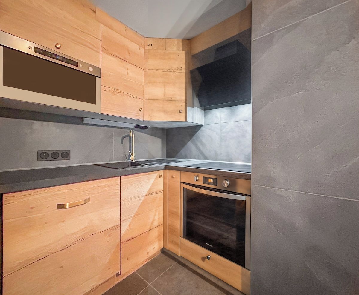 A kitchen with wooden cabinetry, a stainless steel range hood, and a built-in oven.