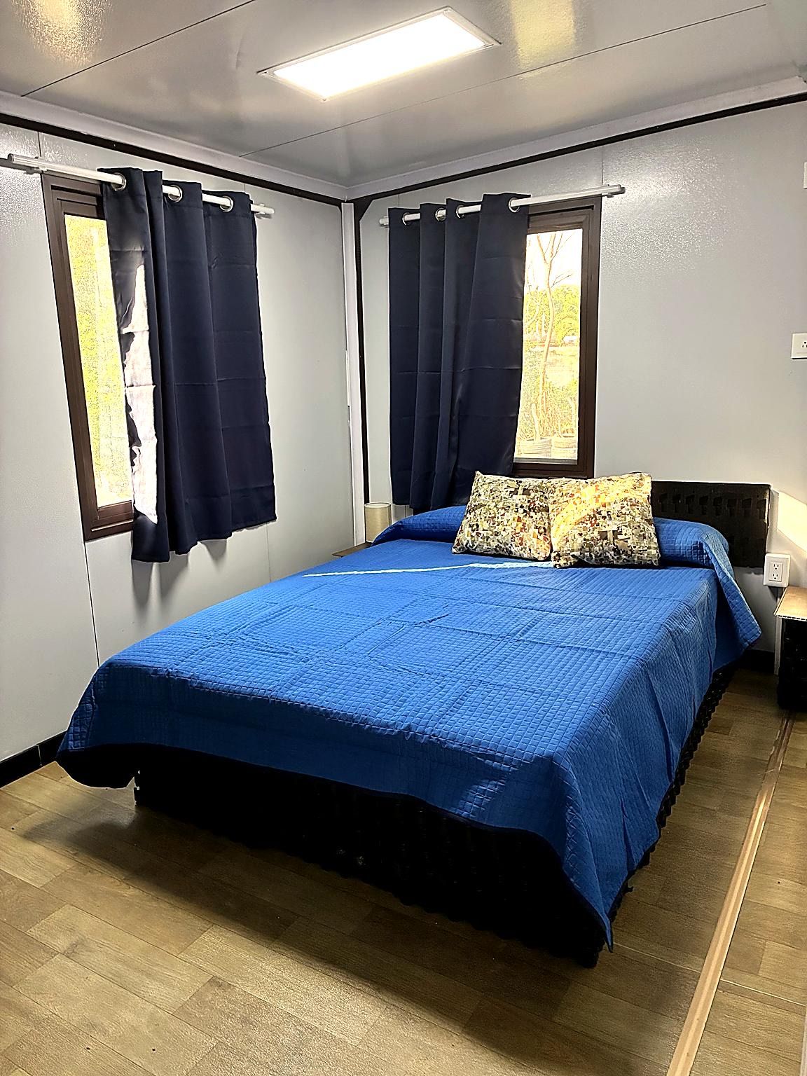 A bedroom with a bed, curtains, a window, and a nightstand.