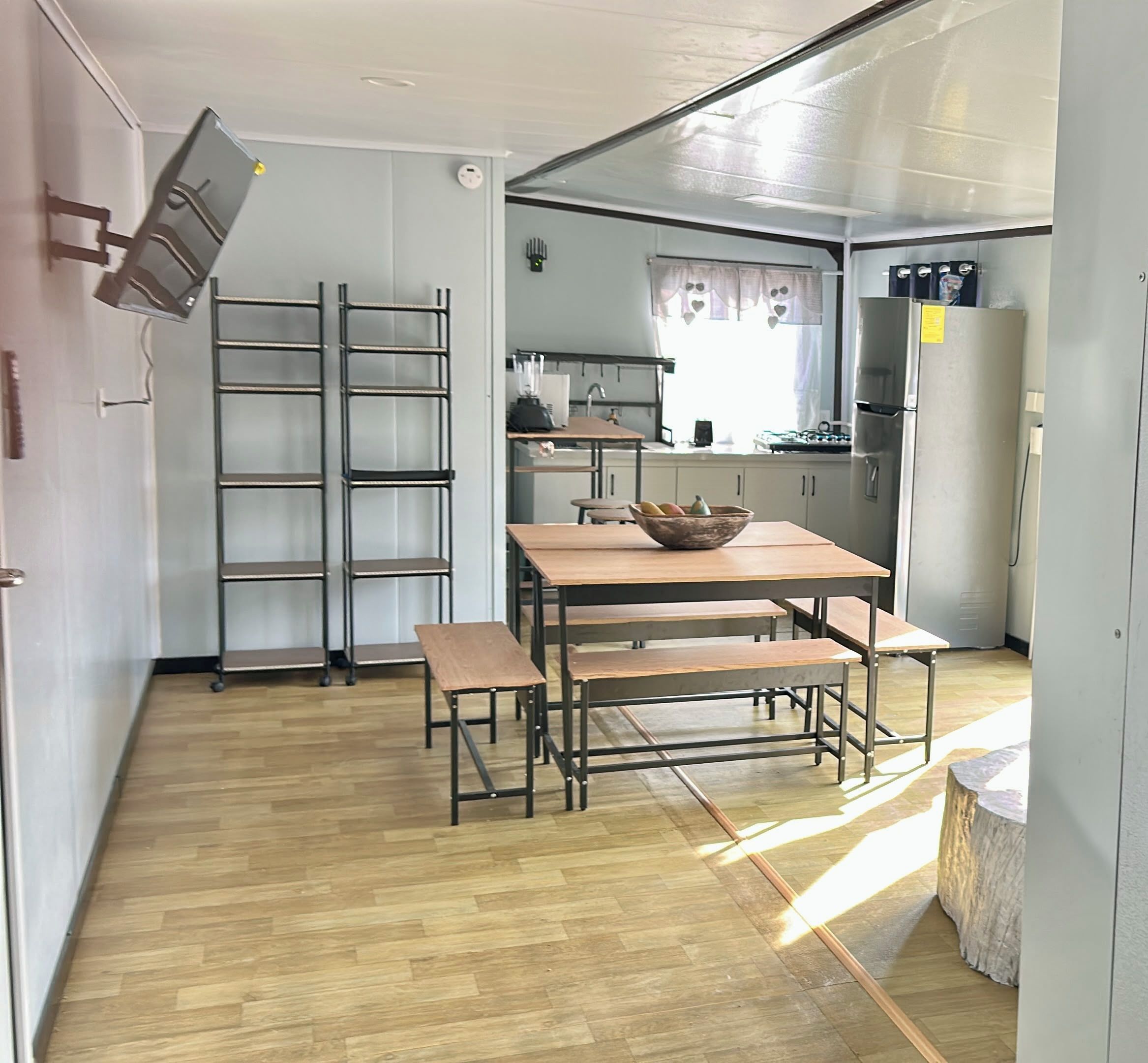 A compact kitchen with a dining area, including a table with benches, a stove, and a refrigerator.