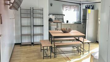 A compact kitchen with a dining area, including a table with benches, a stove, and a refrigerator.