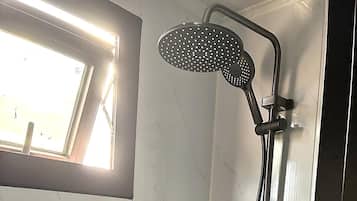 Brusebad med håndbruser og vandhane på væggen.