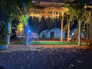 A covered outdoor area with string lights, a pergola, and a seating area with chairs.