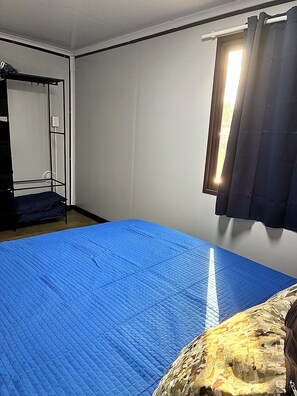 Ein Zimmer mit einem Bett, einem Kleiderschrank und einem Vorhangfenster.