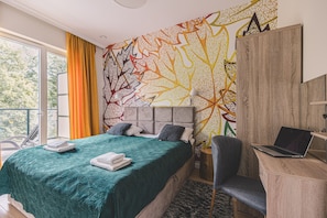 A bedroom with a bed, a desk, and a laptop.
