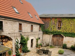 A courtyard with stone walls, a wooden door, and a tiled roof. - Holiday Apartment With 5 Bedrooms (Rathmannsdorf)