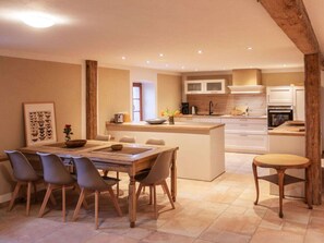 A modern kitchen with a central island, white cabinetry, and a dining area with a wooden table and chairs. - Holiday Apartment With 5 Bedrooms (Rathmannsdorf)