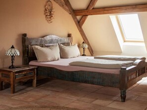 A bedroom with a wooden bed, two bedside tables, a nightstand, a dreamcatcher on the wall, and a skylight. - Holiday Apartment With 5 Bedrooms (Rathmannsdorf)