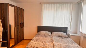 A bedroom with a bed, a wardrobe, and a window with curtains.