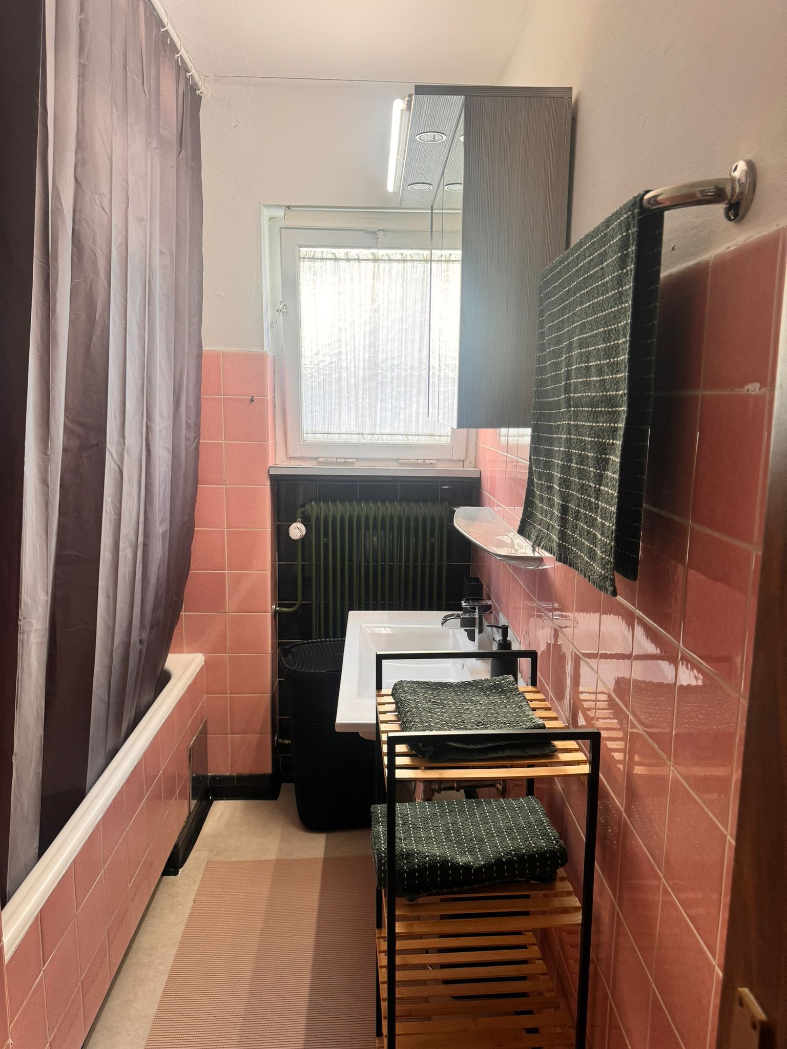 A compact bathroom with a shower, a sink, and a mirror.