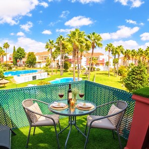 A balcony with a glass table, two chairs, and a bottle of wine. - An exclusive luxury oasis right next to La Barrosa Beach! (Chiclana de la Frontera)