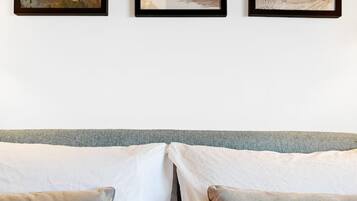 A bed with two pillows and three framed artworks on the wall above.