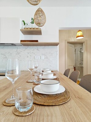 A dining area with a wooden table set for a meal, including plates, bowls, and glasses. - Marsascala 2 bedroom apartment (Wied il-Għajn)