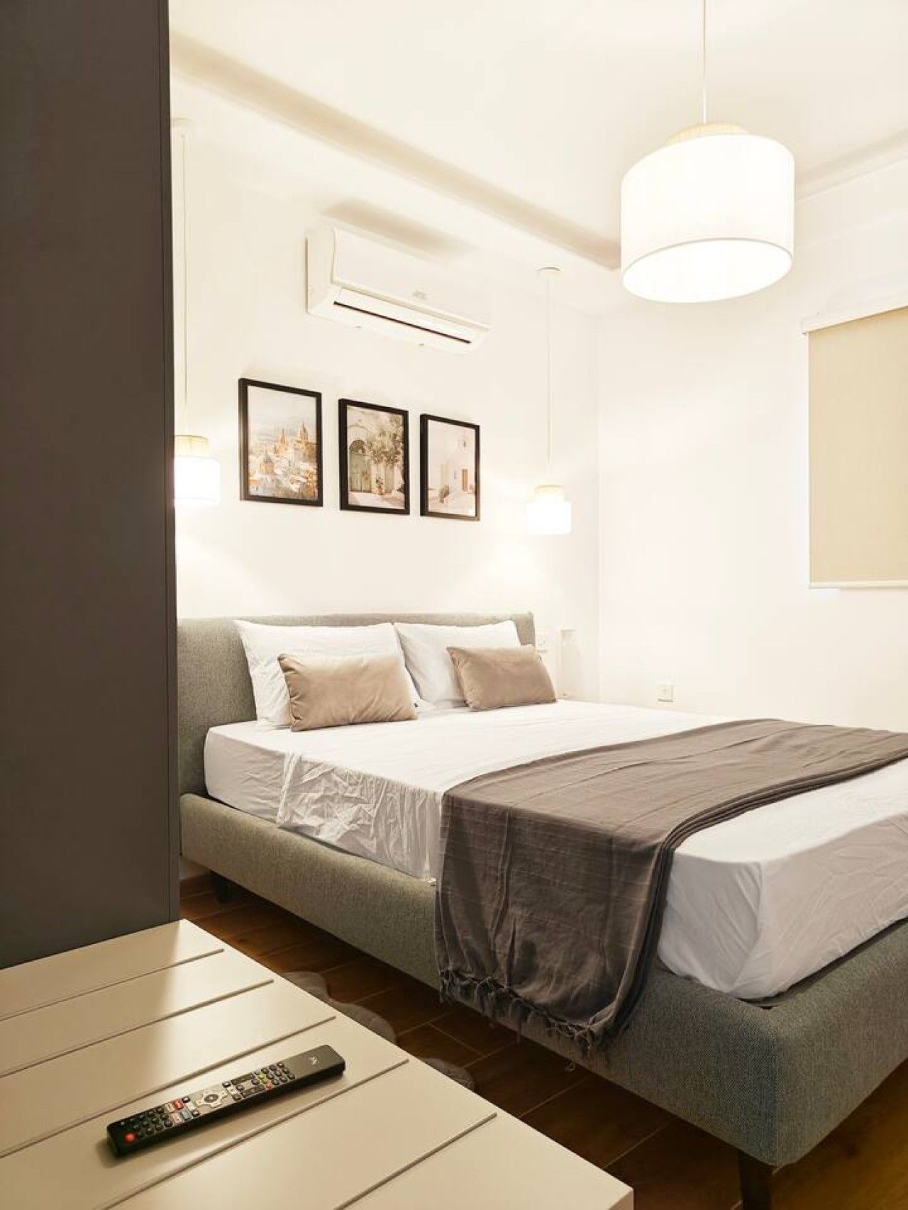 Ein modernes Schlafzimmer mit einem Bett, einem Nachttisch, einer Fernbedienung und Wandbildern.