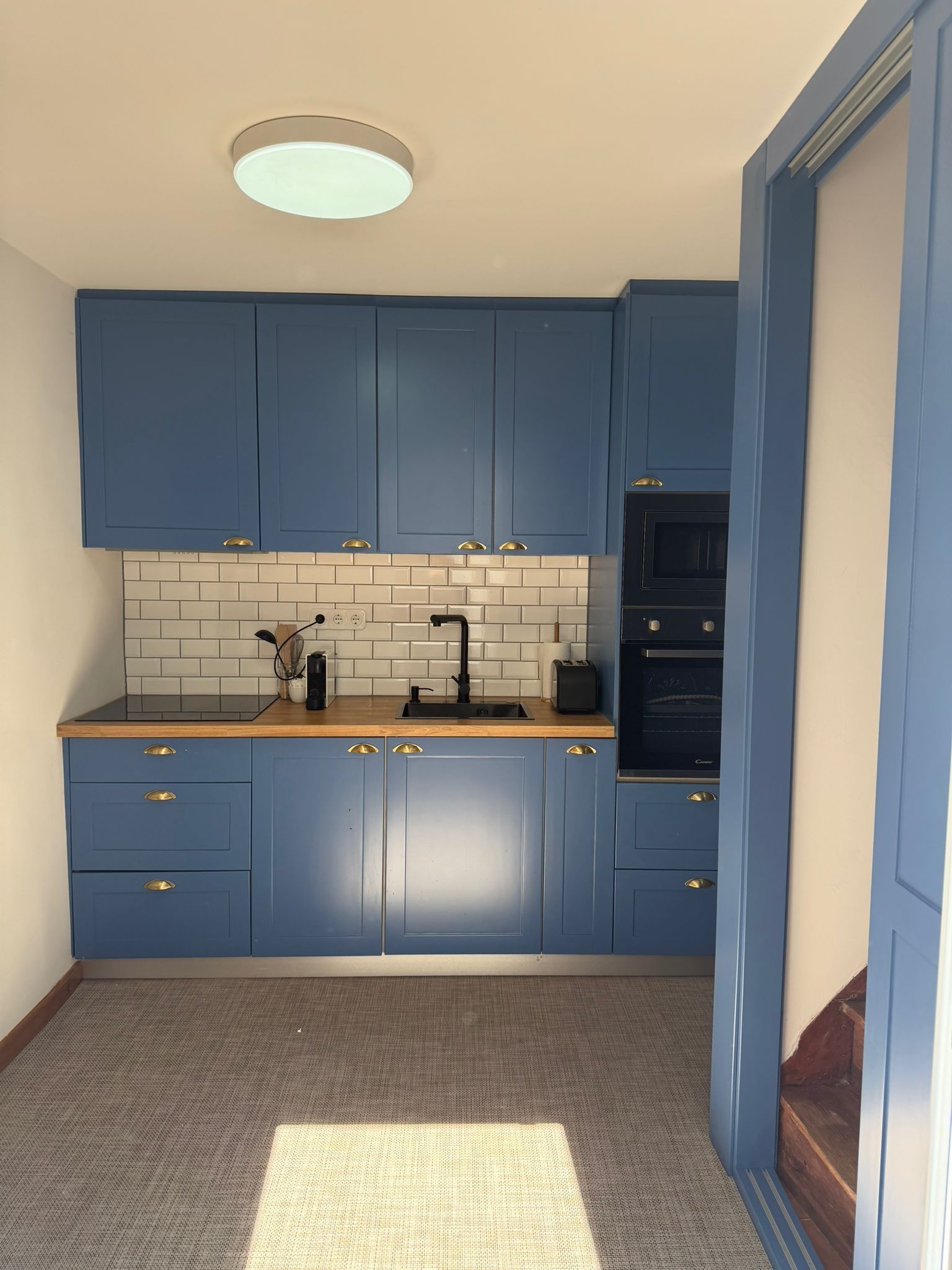Eine Küche mit blauen Schränken, einer schwarzen Arbeitsplatte, einer weißen Fliesenrückwand und einem eingebauten Backofen.