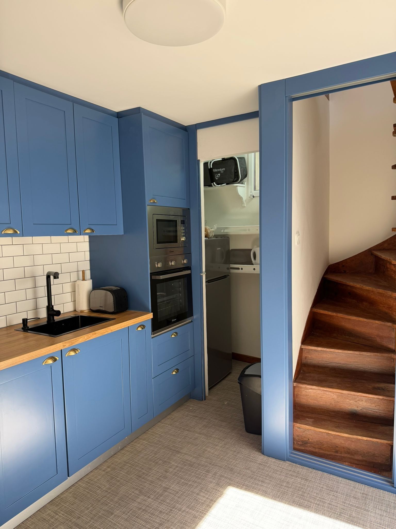 Una cocina compacta con armarios azules, microondas, horno y tostadora.