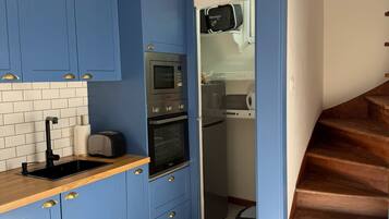 Una cocina compacta con armarios azules, microondas, horno y tostadora.
