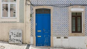 Un edificio con puerta azul, baldosas estampadas y un cartel con grafiti.