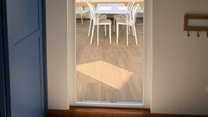 Ein Zimmer mit einer Schiebetür zu einer Terrasse im Freien, mit Tisch und Stühlen.
