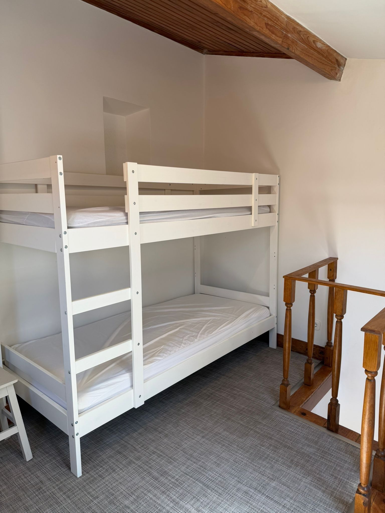 A bunk bed with a wooden headboard and a small wooden table beside it.