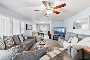 A modern living room with a ceiling fan, a television, and a dining area with a view. - 2416 Dunbar Avenue (Melbourne)