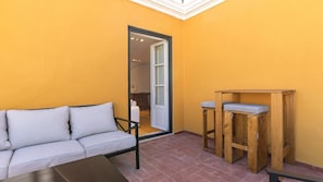 A small patio area with a white sofa, a wooden table, and a wooden bench with cushions. - Chiado Terrace & Castle View 2BR by LovelyStay (Lisboa)