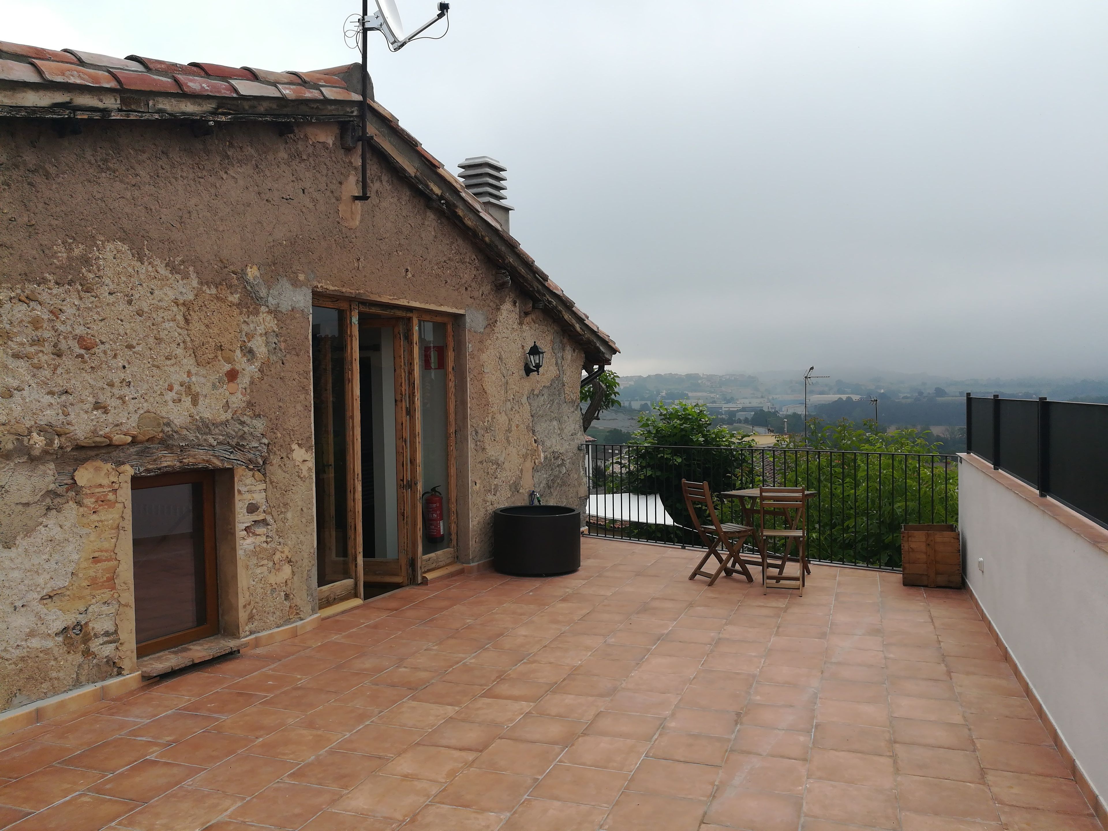 Una construcción rústica con un patio empedrado, una puerta de madera y vistas al campo.