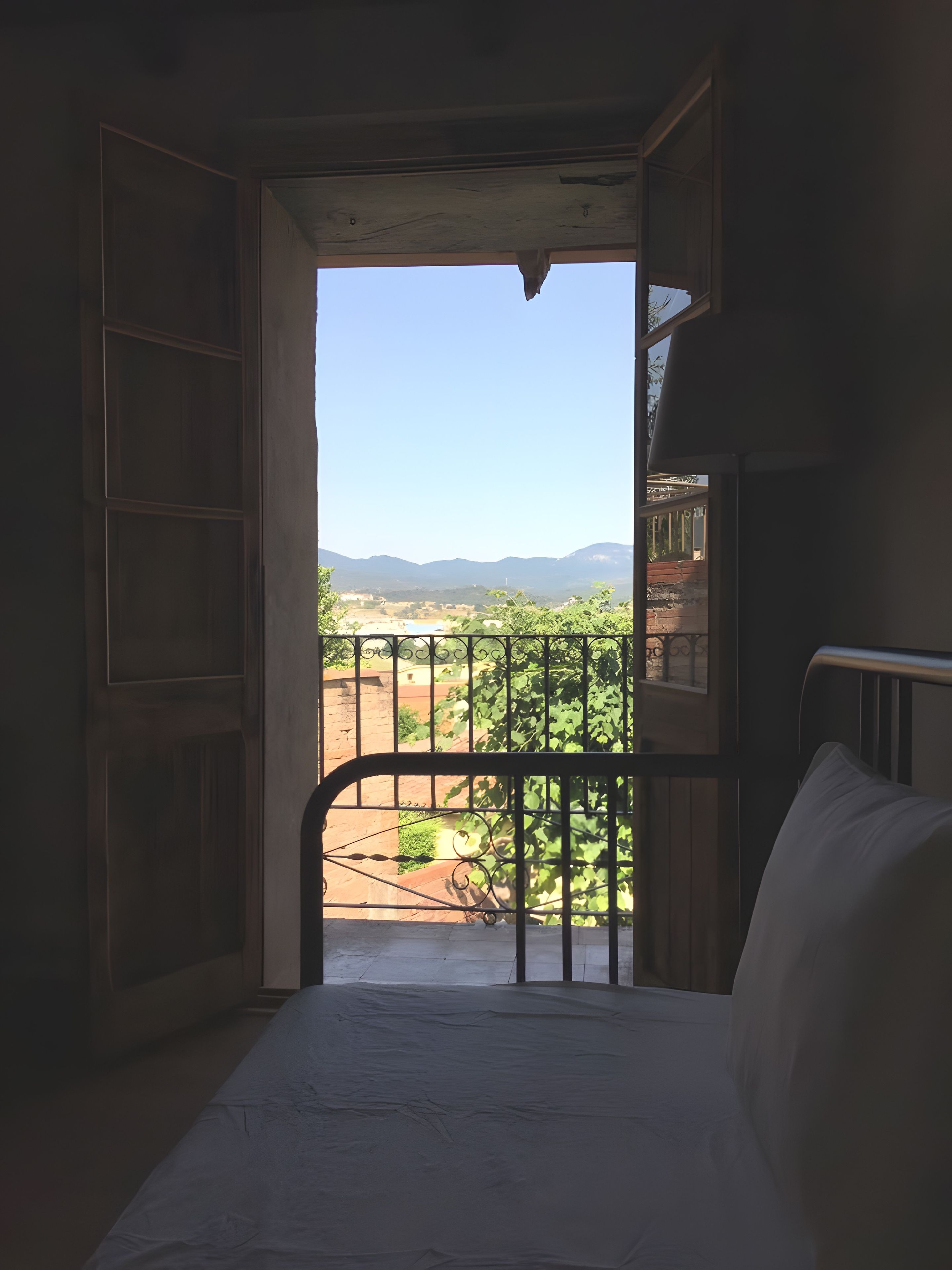Una habitación con una cama, una ventana con vistas al paisaje y una puerta que da al exterior.
