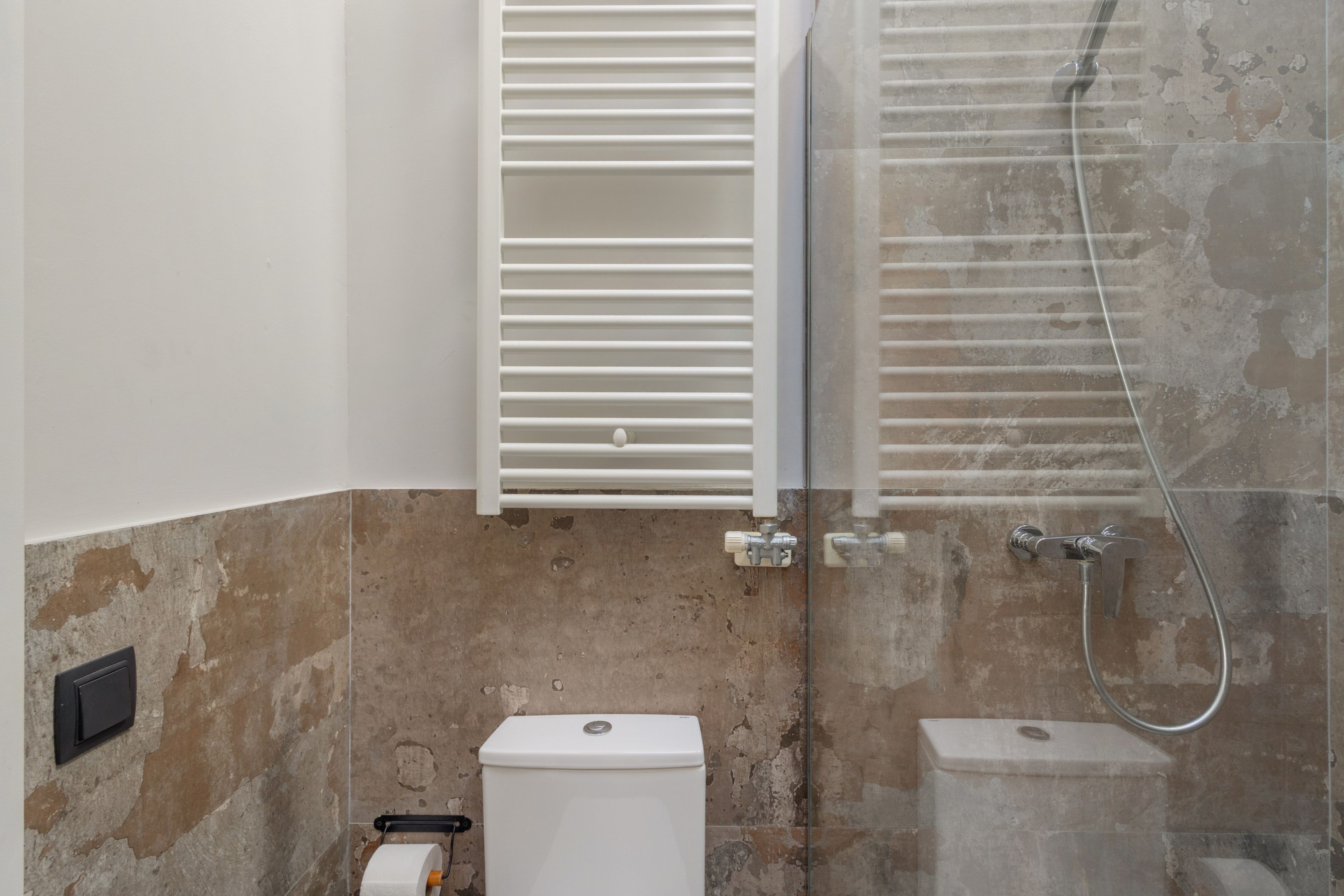 Un baño con inodoro, ducha y toallero.