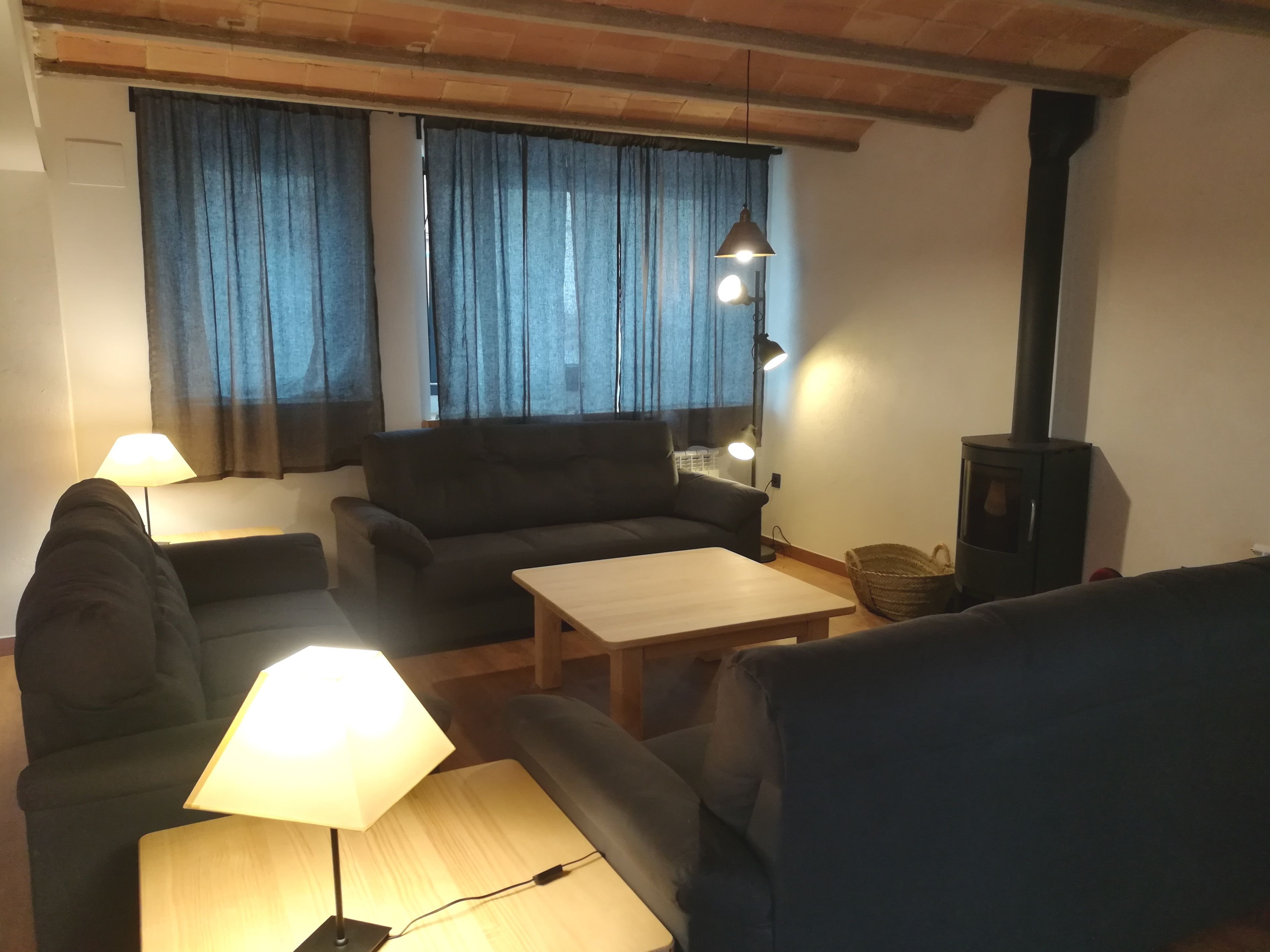 En hyggelig stue med en sofa, to lænestole, et sofabord og en pejs.