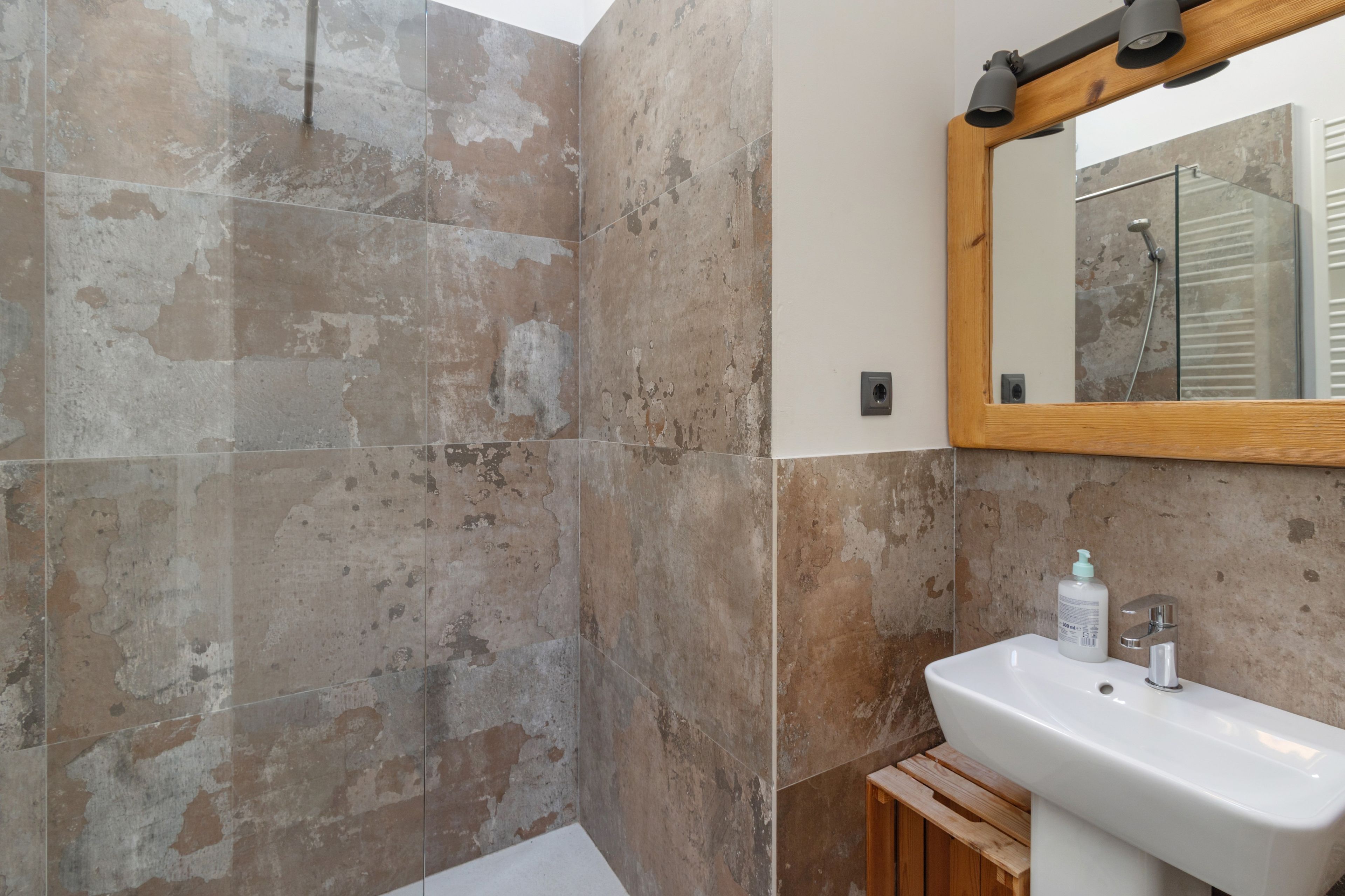 A bathroom with a shower, a sink, and a mirror.