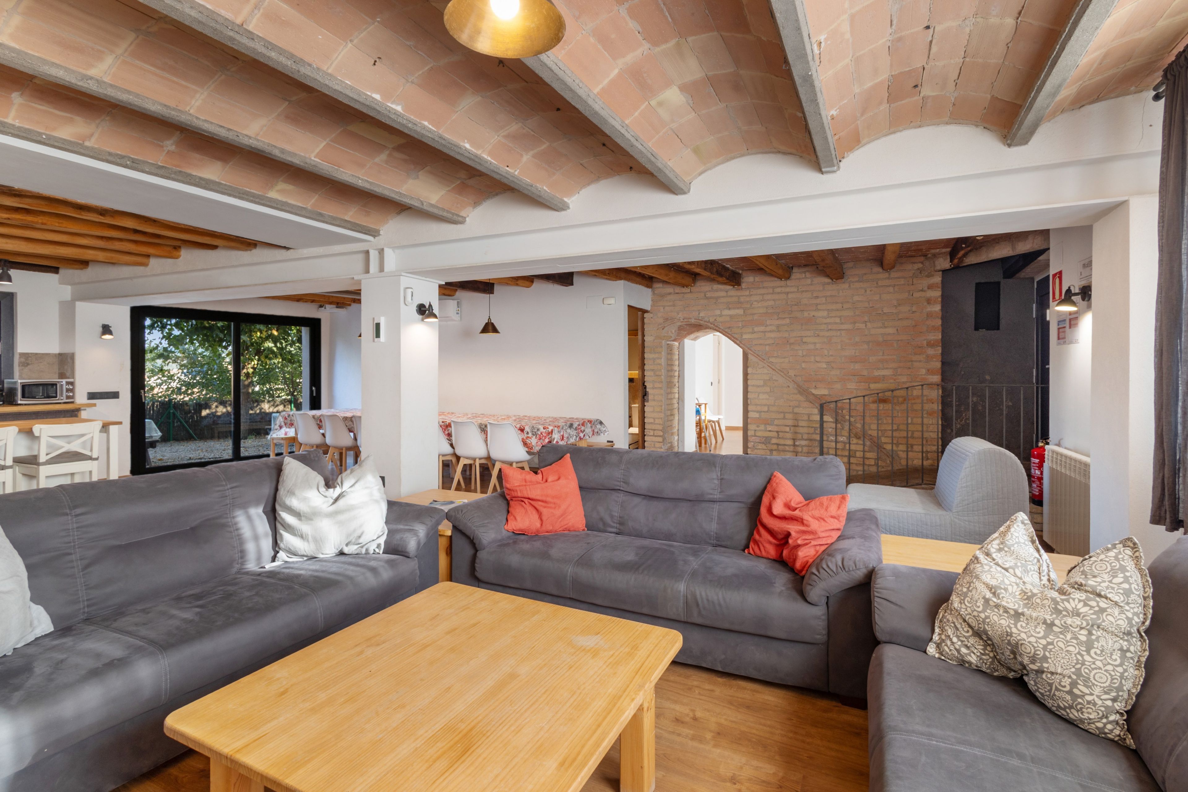 Una sala moderna con sofás grises, una mesa de centro de madera y una pared de ladrillo.