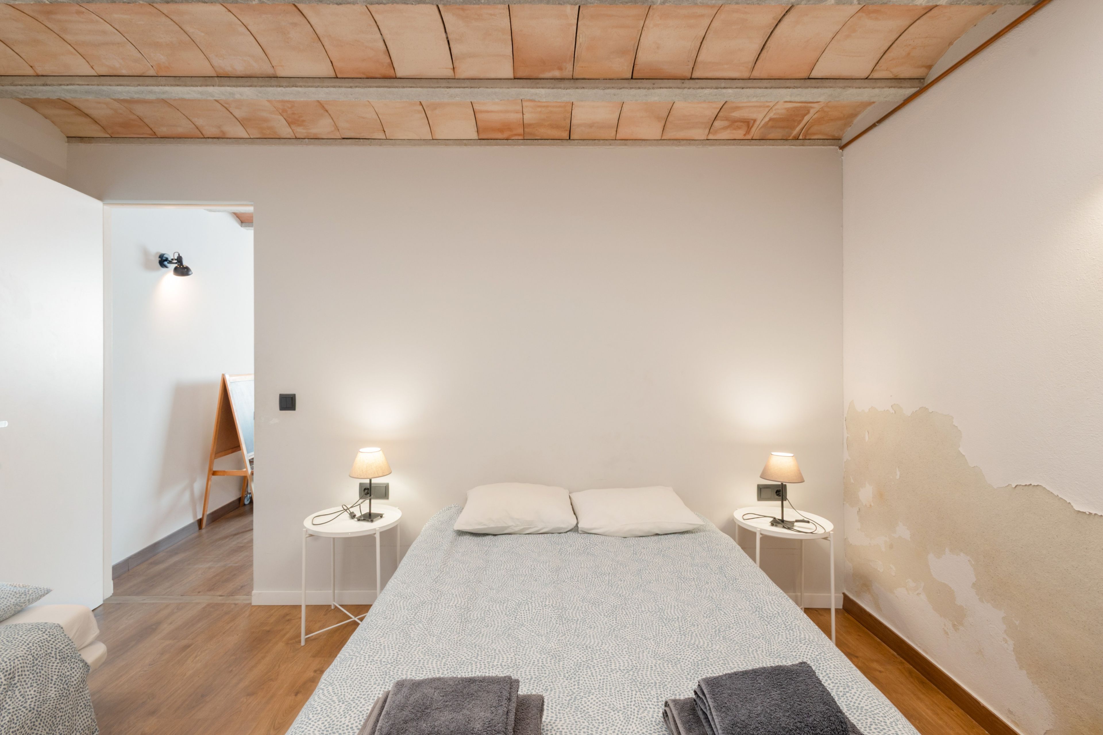 Ein Schlafzimmer mit einem großen Bett, zwei Nachttischlampen, Holzboden und einer weißen Wand.
