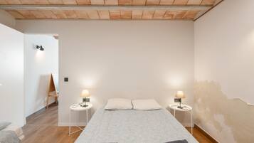 Ein Schlafzimmer mit einem großen Bett, zwei Nachttischlampen, Holzboden und einer weißen Wand.