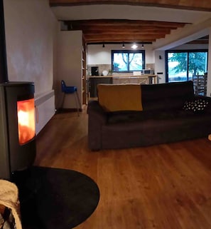 A living room with a sofa, a fireplace, and a view into the kitchen area.