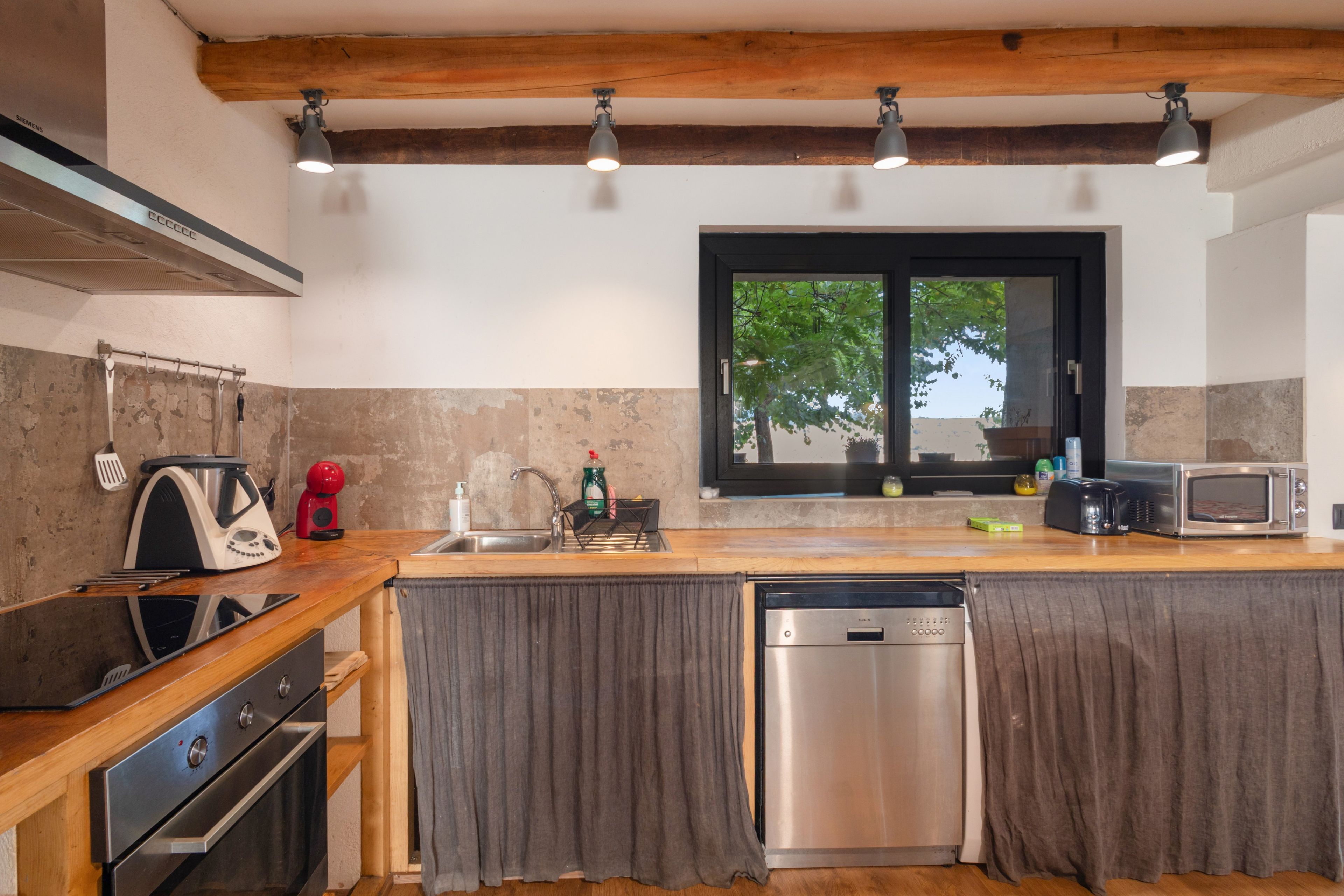 Una cocina moderna con lavavajillas integrado, estufa y microondas.