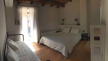 Un dormitorio con una cama, mesita de noche, lámpara y ventana con cortinas.