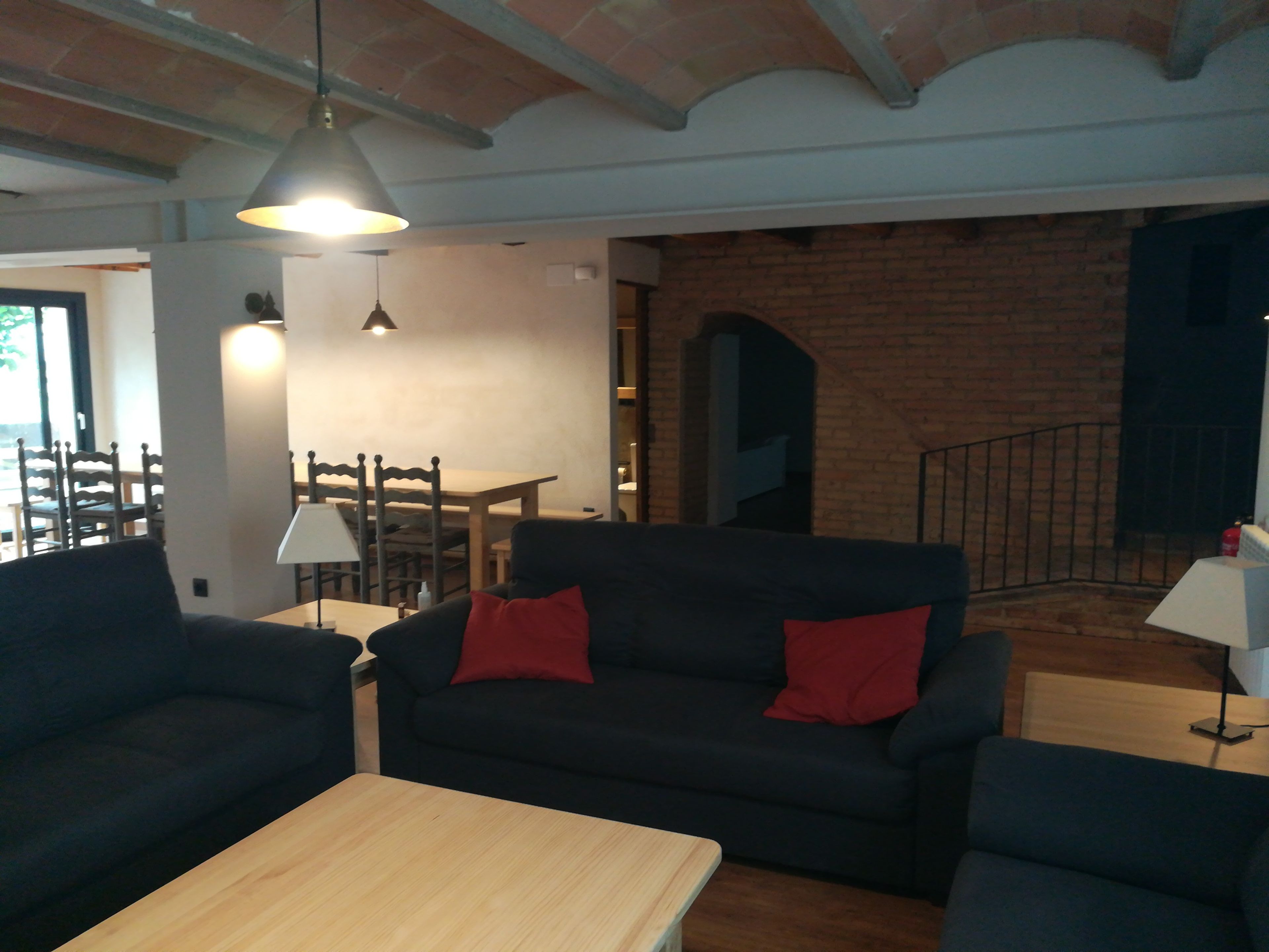 Una sala de estar con un sofá de color oscuro, una mesa de centro de madera y un comedor con mesa y sillas.