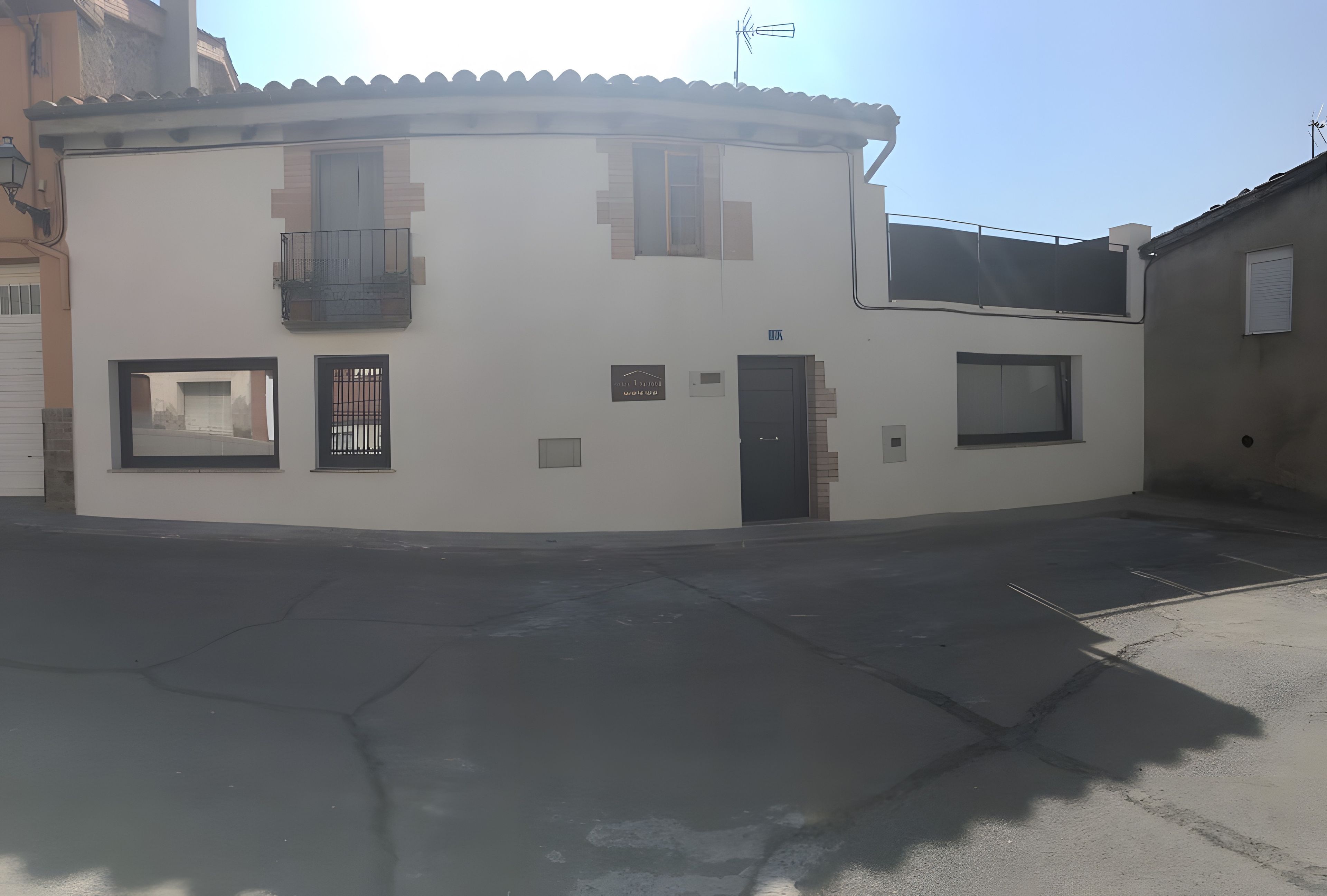 Un edificio en esquina con acceso por una rotonda, una puerta y dos ventanas.