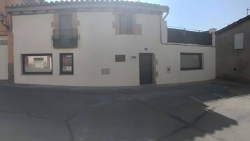Un edificio en esquina con acceso por una rotonda, una puerta y dos ventanas.