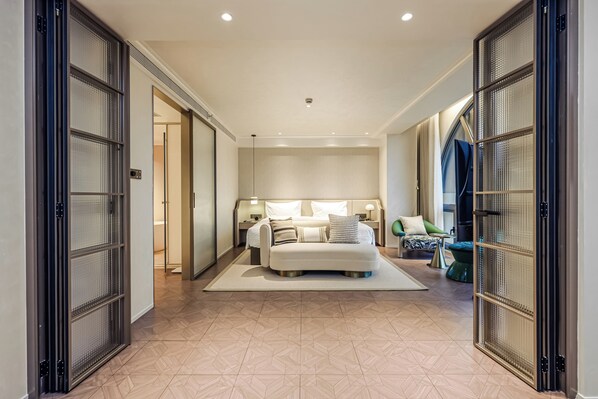 Une chambre d’hôtel avec un lit, des tables de chevet, un canapé et une télévision.