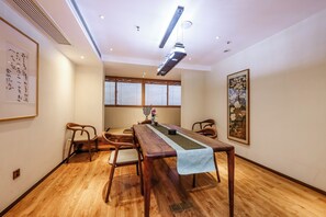 Una habitación con una mesa de comedor de madera, sillas, una lámpara de techo y una obra de arte enmarcada en la pared.