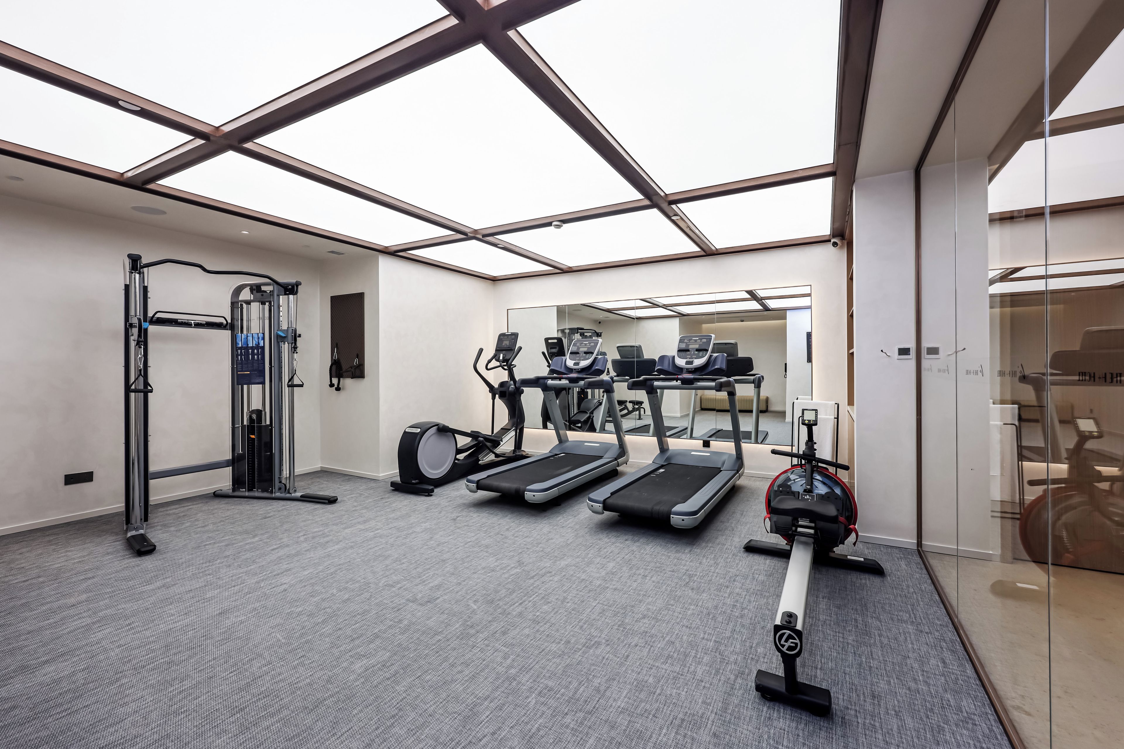 Un gimnasio con equipamiento de ejercicio que incluye una barra de dominadas, cintas de correr y una máquina de remo.