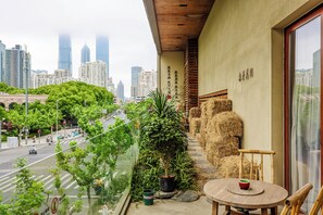 Un balcón con vista a un paisaje urbano, una mesa con una taza y una planta en maceta.