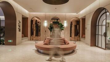 A modern lobby with a central seating area, mirrored walls, and a ceiling with recessed lighting.