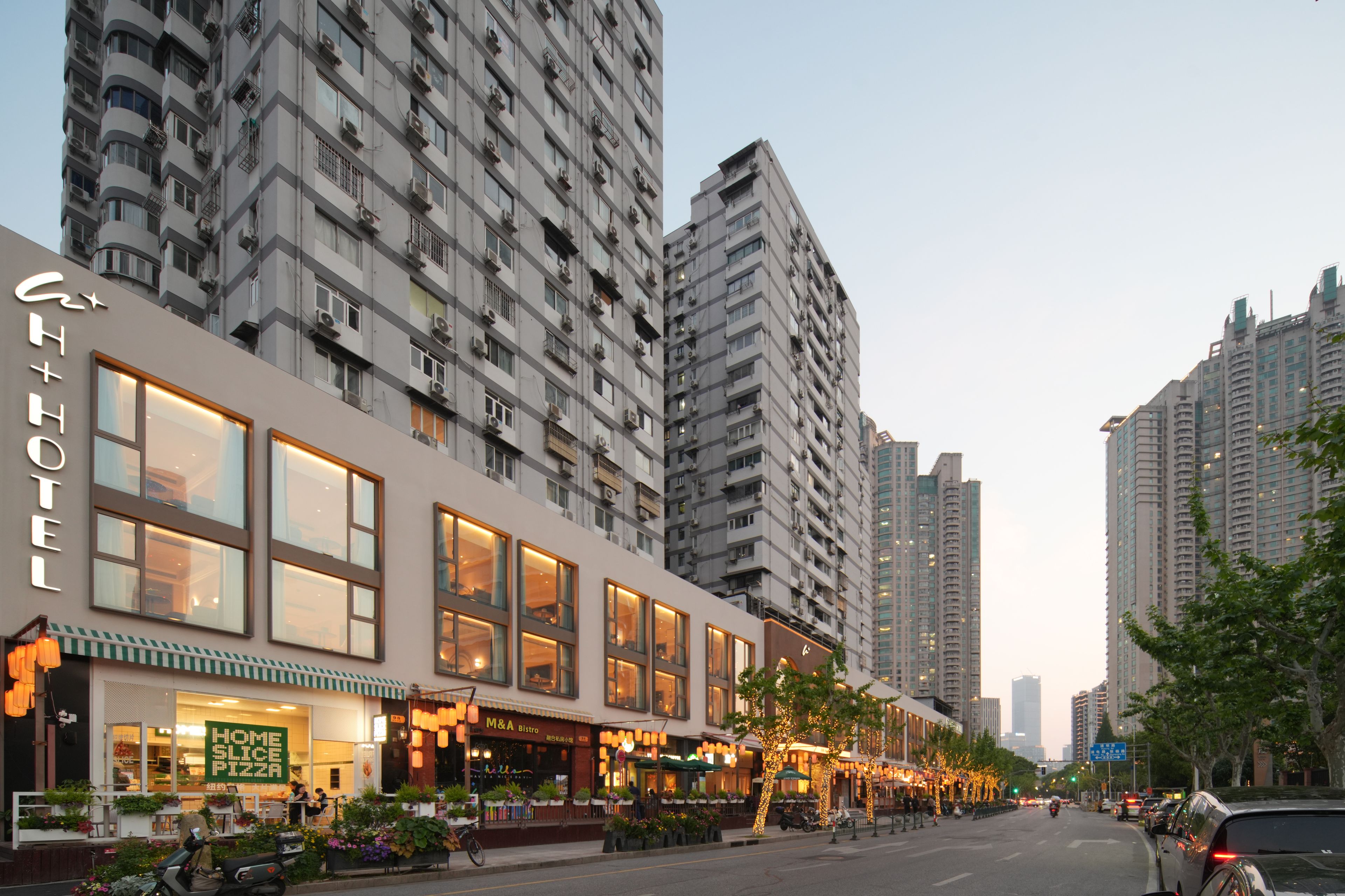 Un hotel con fachada moderna, amplias ventanas y mesas al aire libre.