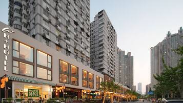 Un hotel con fachada moderna, amplias ventanas y mesas al aire libre.