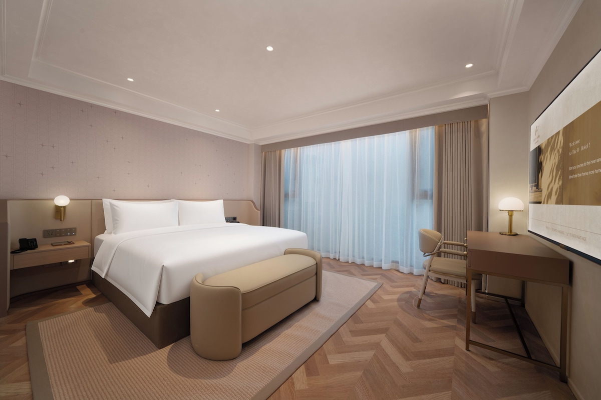 Una habitación de hotel moderna con una cama grande, mesitas de noche, un escritorio y una silla.