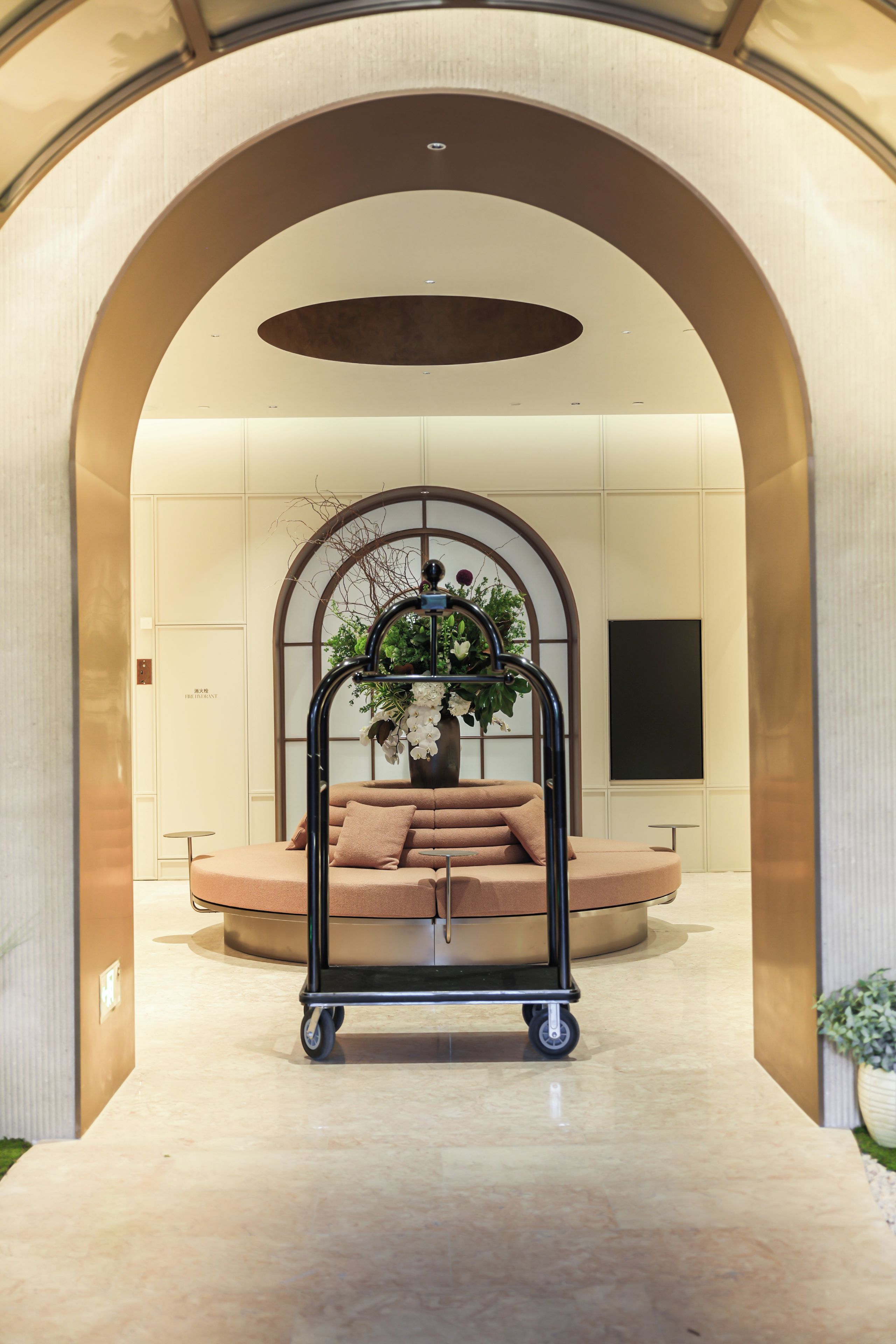 A modern lobby with a central seating area, a decorative cart, and a large window.