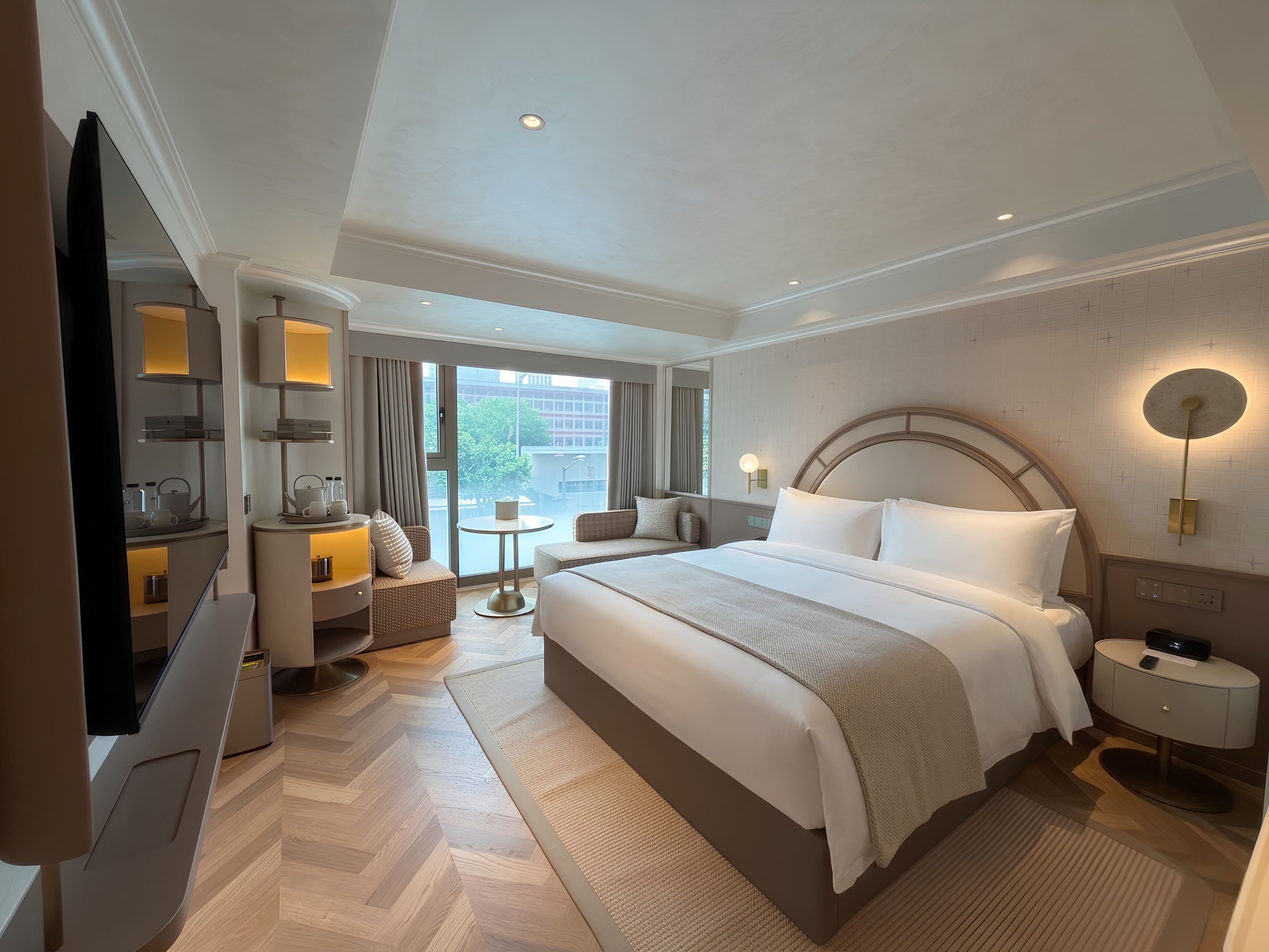 Habitación de hotel moderna con una cama grande, televisión, zona de estar y vistas a la ciudad.